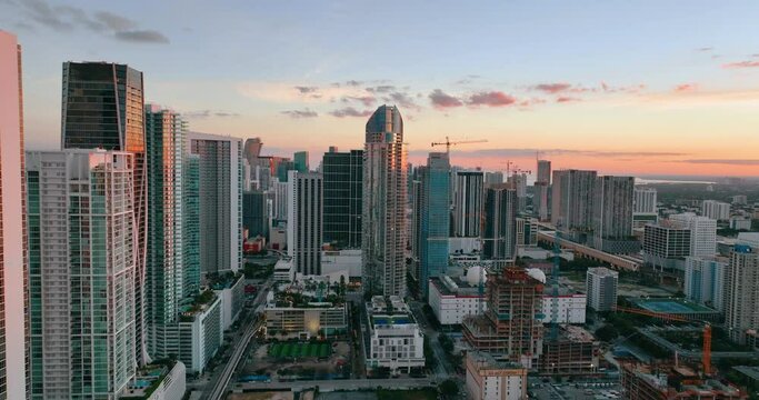 Aerial view evening city with skyscrapers and urban buildings against clear sky. Cityscape of Miami, Florida. Bright sunset with reflection in windows of houses.