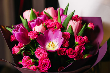 Vibrant Tulips and Roses Bouquet in Purple Wrap. A bouquet of pink tulips and roses beautifully arranged and wrapped in a purple paper, ideal for a romantic gift or special occasion.