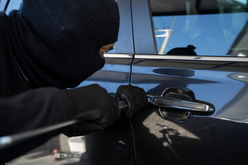 Masked burglar trying to get into a car