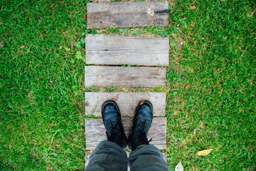 Top view of feet in black army boots, selfie against the background of a path of boards and grass, lawn, decision-making, the concept of choosing where to go, the beginning of the path, tourism