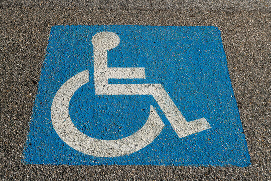 parking for disabled people, symbol printed on the asphalt, parking space reserved for cars for disabled people and their companions, road sign