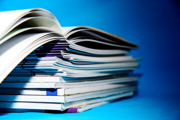 Stack of magazines on a blue background, isolated in a university library Education concept - obrazy, fototapety, plakaty
