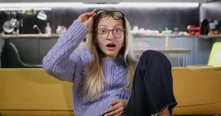 Woman donned in glasses tries to see information on screen. Spending time in front of TV on regular basis influences badly eyesight