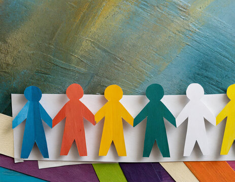 group of colourful cutout paper people holding hands