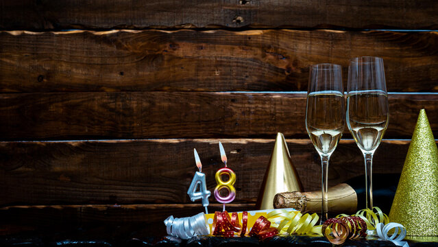 Solemn background for the anniversary with the number  48. Happy birthday background on brown wooden background with champagne bottle and champagne glasses. Beautiful holiday decorations copy space.