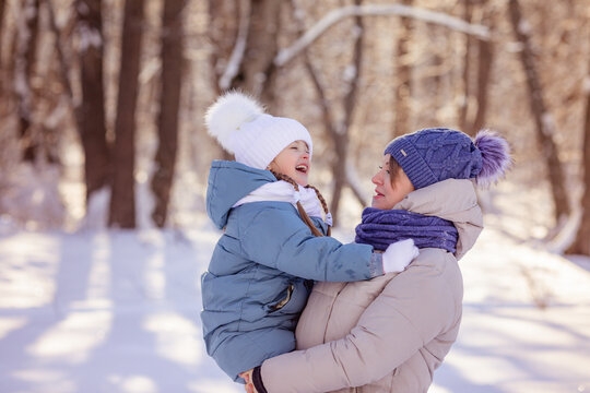 Mom with little daughter in winter in the forest or city park. Winter activities concept image. Happy family time