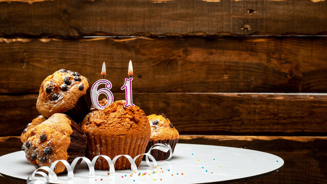 Pies with a number 61  of candles burning for the anniversary. Copy space background happy birthday on wooden background. Card or postcard festive rustic brown.