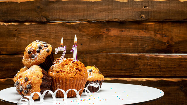 Pies with a number 71 of candles burning for the anniversary. Copy space background happy birthday on wooden background. Card or postcard festive rustic brown.