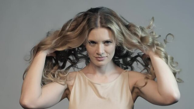 Slow motion video of woman throws up long curly hair with hands. Female hair beauty concept.