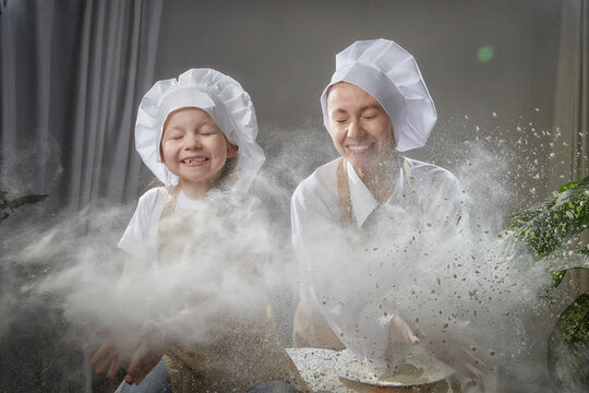 Cute oriental family with mother, daughter cooking in the kitchen on Ramadan, Kurban-Bairam, Eid al-Adha. Funny family at cook photo shoot with flour. Pancakes, pastries, Maslenitsa, Easter