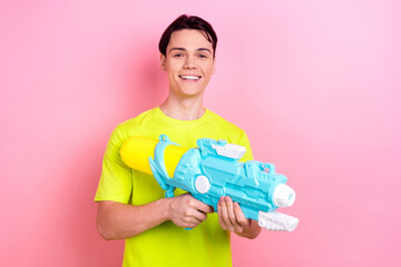 Photo portrait of handsome teen male hold water gun playful wear trendy yellow garment isolated on...