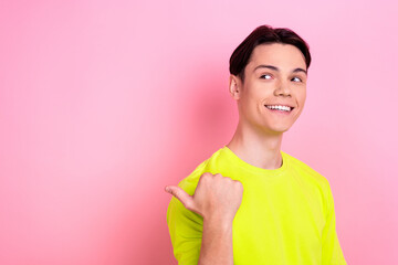 Photo portrait of nice teen man point look empty space toothy smile wear trendy yellow clothes isolated on pink color background