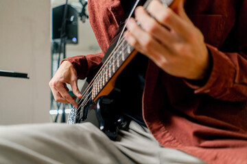 musician with electric guitar in recording studio plays musical instrument presses fingers on...