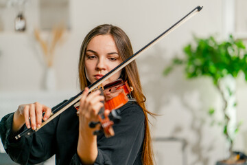 A girl violinist rehearses the melody of a classical piece of music on the violin in a music center...