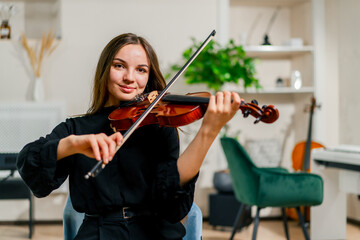 A girl violinist rehearses the melody of a classical piece of music on the violin in a music center...