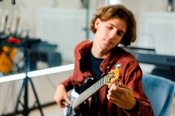 Fototapeta na wymiar a musician with an electric guitar during a rehearsal in a recording studio adjusts the strings and the sound of the musical instrument