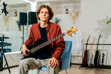 Obraz premium portrait of a young musician with long hair holding an electric guitar in his hands in a recording studio