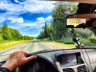 Car salon, steering wheel, hand of woman and view on nature landscape. View from seat of driver on...