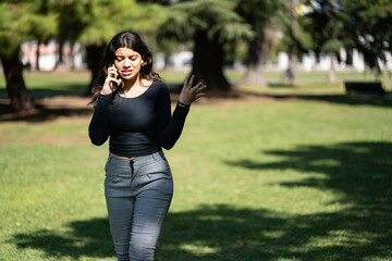Latin teen girl talking on the phone in a park