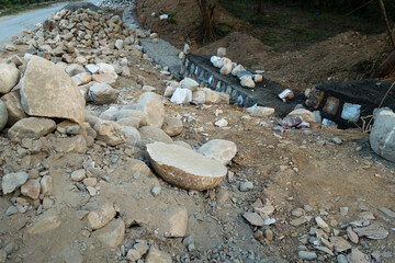 A pile of stone alongside road for constructing a stone retaining wall to prevent landslide and...