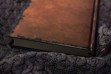 Brown book on a knitted plaid. Cozy interior.
