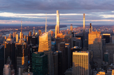 Midtown Manhattan Billionaires Row supertall skyscrapers illuminated by warm light. Aerial view of New York City at sunset