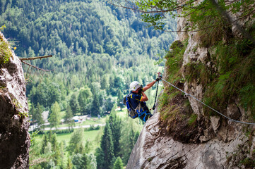 middle age climber in a good sport shape in full equipment climb Slovenian ferrates