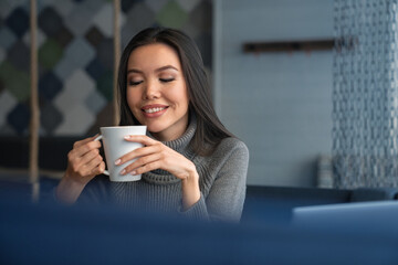 Fototapeta premium Businesswoman enjoying her coffee break after work day at the office. Aroma with hot beverage after shift at workplace. Boost of energy after caffeine