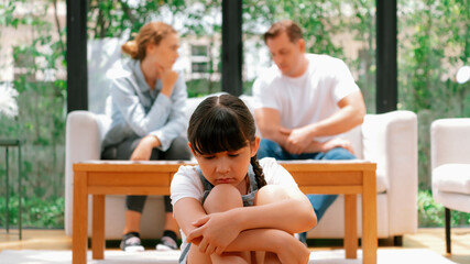 Stressed and unhappy young girl crying and trapped in middle of tension by her parent argument in...
