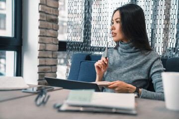 Thoughtful beautiful woman sitting on a couch with looking outside in cafe. Creating new ideas,...