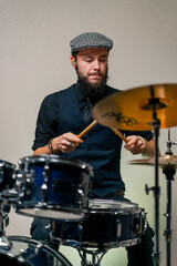 bearded male musician during rehearsal plays drums musical instrument drumsticks music concert