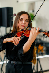 Girl violinist concentrates on performing a classical melody during a violin rehearsal in a music...