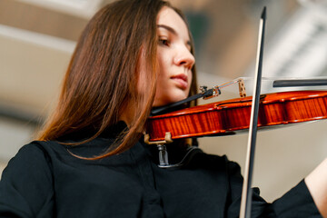 Close-up of a girl holding a violin with her fingers, fingering the strings to perform a classical...