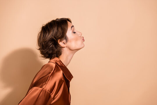 Photo of flirty adorable woman wear silky blouse closed eyes kissing empty space isolated beige color background