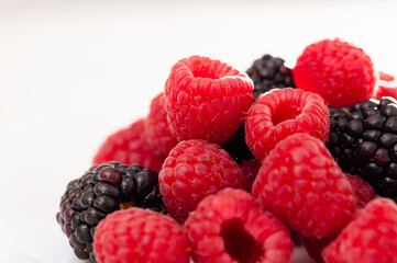 Handful of raspberry and blackberry berries on white background