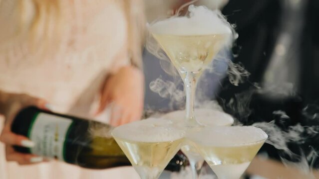 People pour champagne from a bottle into glasses. Close-up shooting in slow motion
