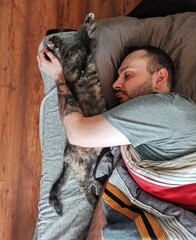 Young man sleeping with his cat in the bed.