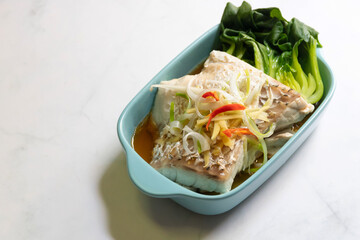 Sea bass fillet steam with soy sauce. Top view on table background.