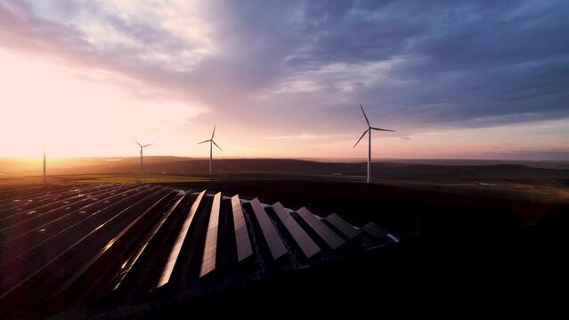 Solar panels park and wind turbines at sunset.Windmill turbines generating green energy electric.Green energy  reduce carbon emissions and makes earth cleaner and more ecological.