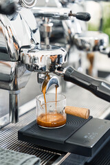 Espresso machine making hot coffee into dosing cup in coffee shop