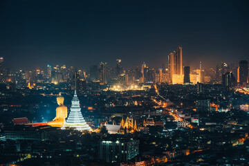 Obraz premium Cityscape of Bangkok night scene with building exterior, buddha in temple and department store glowing in downtown