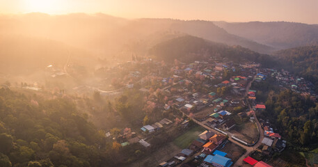 Sunrise over Thai tribe village in foggy with wild himalayan cherry tree blooming at Ban Rong Kla, Thailand