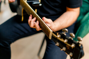 musician with electric guitar in recording studio plays musical instrument presses fingers on...