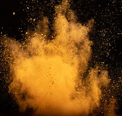 Explosion of orange powder, dust smoke on black background