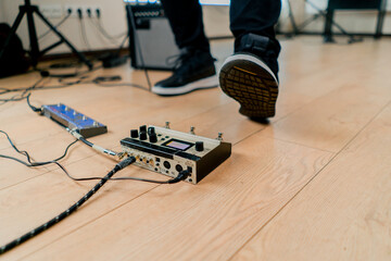 musician's male foot pressing bass drum pedal or bass electric guitar in recording studio close-up