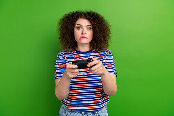Photo of concentrated girl biting lips hold controller locked playing games isolated on green color...