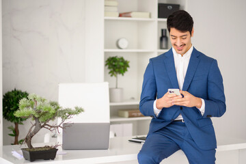 The businessman checks his smartphone with a focused expression, standing in a minimalist office...