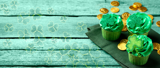 St. Patrick's day. Tasty cupcakes with clover leaf toppers and cream on green wooden table,...