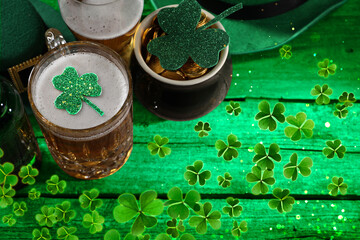 St. Patrick's day. Beer, leprechaun pot of gold and decorative clover leaves on green wooden table, above view. Space for text