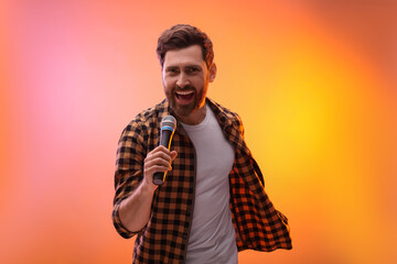 Handsome man with microphone singing in color lights
